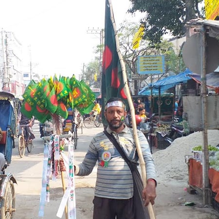 জাতীয় পতাকা বিক্রি করে বাড়তি আয় জয়পুরহাটের হেমায়েত মাতবরের
